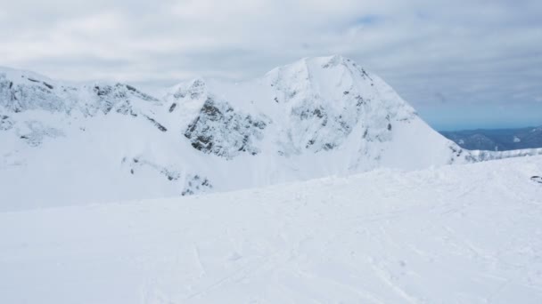 Un skieur en costume lumineux arrive au sommet de la montagne, regarde les montagnes enneigées, 4k . — Video