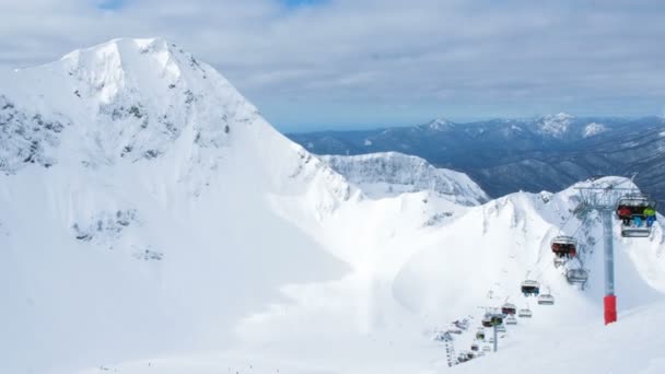 Open vierzitter stoeltjesliften in de bergen brengen de skiërs en snowboarders, 4k. — Stockvideo