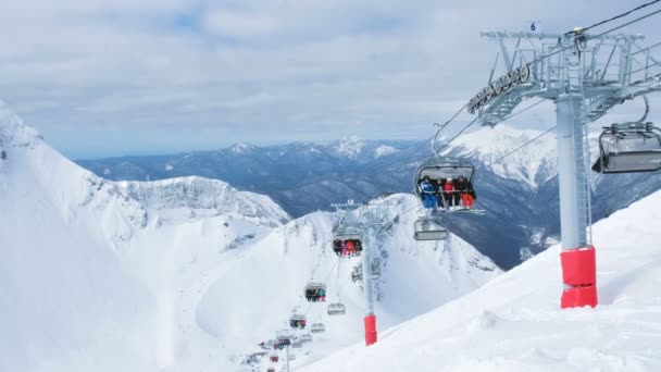 Vierer-Sessellifte in den Bergen bringen Skifahrer und Snowboarder zum Ausgangspunkt der Abfahrt, 4k. — Stockvideo