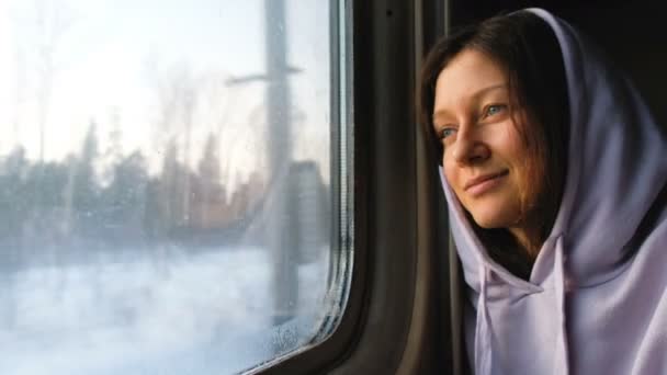 Beautiful caucasian girl looking out the window at sunset on a train, 4k. — Stock Video