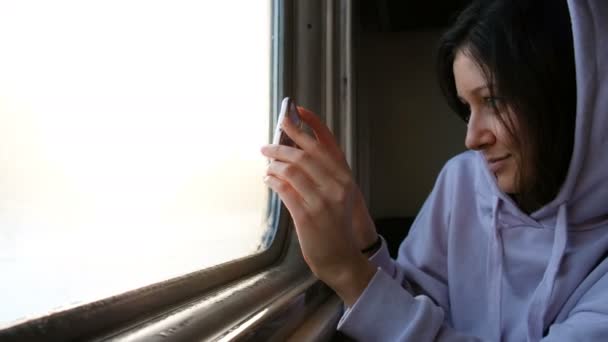 Mooie Kaukasische meisje is fotograferen op de telefoon-weergave van het venster, 4k. — Stockvideo