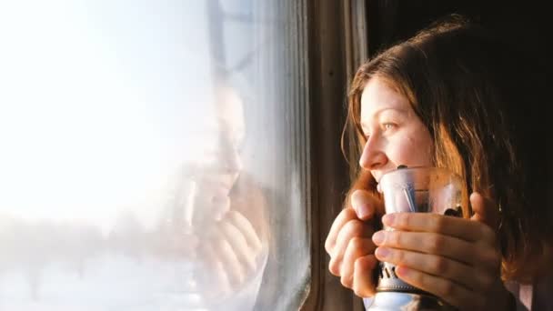 Hermosa chica caucásica monta un tren, bebe té y mira por la ventana, 4k . — Vídeos de Stock