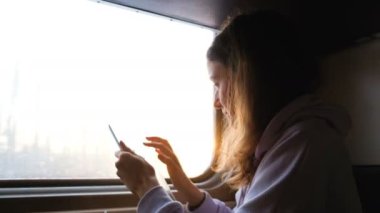 Güzel beyaz bir kadın günbatımı, 4 k arka plan üzerinde trende tablet kullanma.