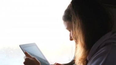 Güzel beyaz kız metni yazdırır ve tablet bir tren günbatımı arka plan, 4 k üzerinde çizer.