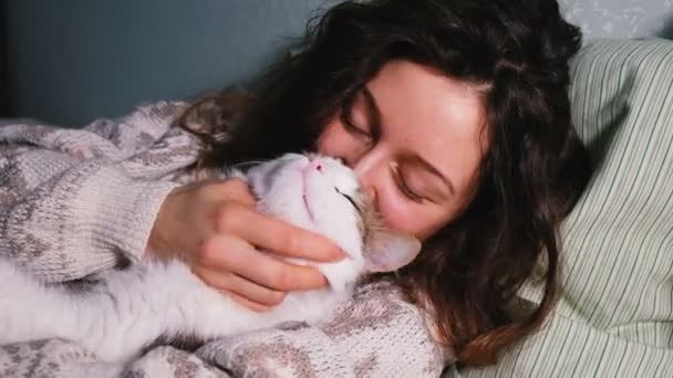 Junges Mädchen mit einer Katze sonnt sich im Bett — Stockvideo