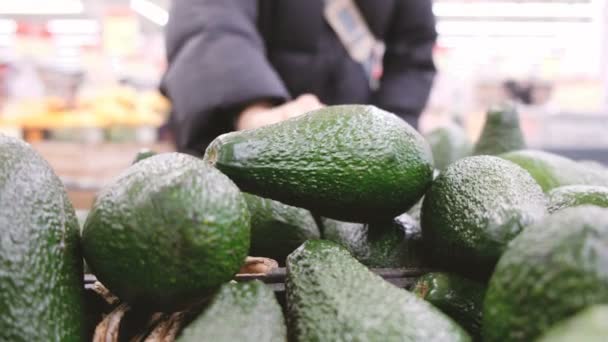 Женщина выбирает спелый авокадо в магазине — стоковое видео