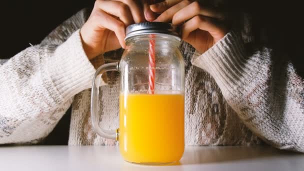 Mädchen trinkt Orangensaft aus einer Glasflasche mit Strohhalm, das Saftvolumen wird reduziert — Stockvideo