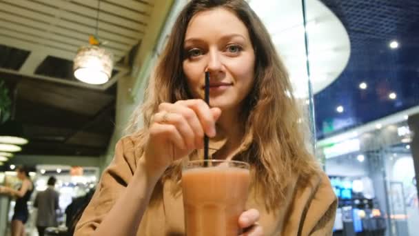 Красивая девушка пьет смузи в кафе — стоковое видео