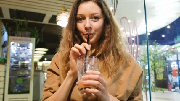 Jeune fille propose de boire des smoothies du tube dans un café — Video
