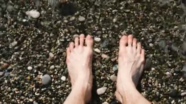 Dalgalar deniz tarafından erkeksi çıplak ayakları yıkanır