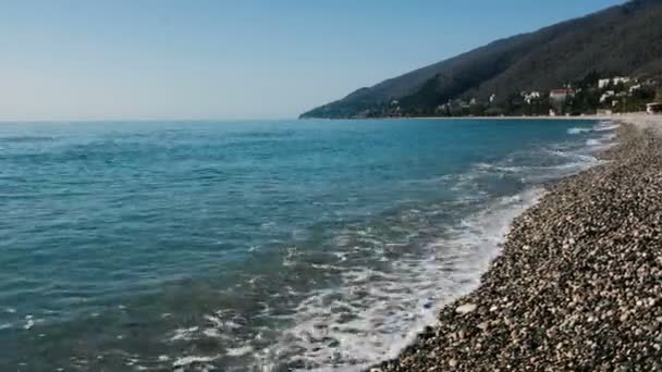 Azuurblauwe zee met een magistrale strand in de achtergrond van een kustplaats — Stockvideo