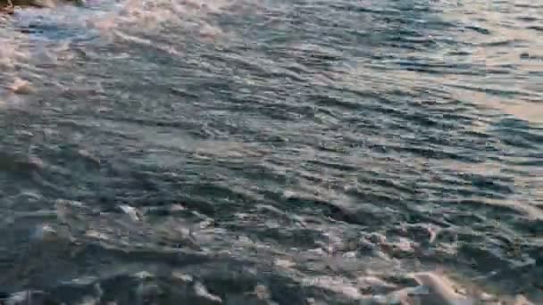 Mavi dalgalar üzerinde bir çakıl plajı gün batımında yakın çekim — Stok video