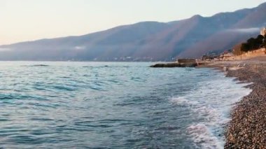 Dalgalar dağlar çerçevede gün batımında denizde