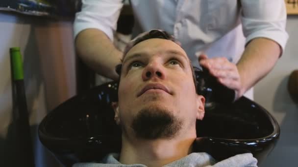 Fodrász ember hajmosás samponnal, a fodrászatban — Stock videók