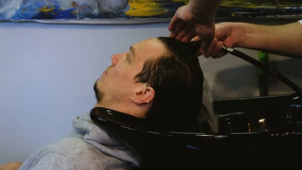 Fodrász mossa a fejét az ember egy szépségszalonban — Stock videók