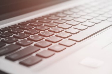 Laptop klavye tuşları ve sıcak tonlu arka plan bokeh odaklı