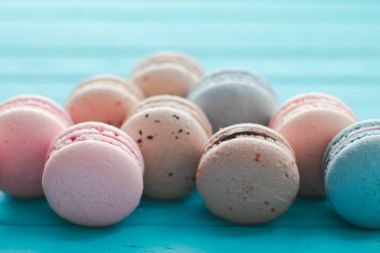 Çok renkli macarons veya macaroons turkuaz ahşap zemin, pastel tonlarda Badem Çerezler