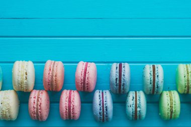 Pasta macaron veya macaroons Dama Tahtası deseni, üstten görünüm yakın çekim, kopya alanı turkuaz ahşap arka plan üzerinde yalan