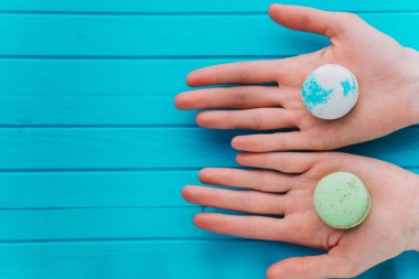Kız macaroons veya turkuaz bir arka plan üzerinde macarons öneriyor. Üstten Görünüm, kopya alanı