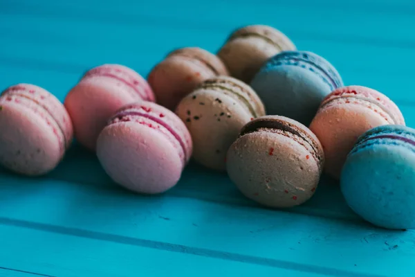 Tarka macarons vagy macaroons a türkiz fa háttér, pasztell színekkel mandulás sütik — Stock Fotó
