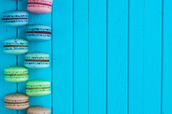 Cookies macaron ou macarons ou biscuits aux amandes reposent sur un fond turquoise en bois motif damier, espace de copie — Photo