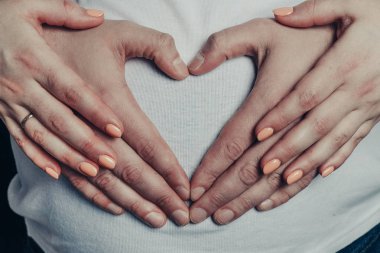 Veliler bir kalp hamile anne yakın çekim karnına yapmak.