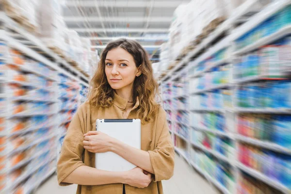 Piękna kobieta z tabletem stoi w supermarkecie — Zdjęcie stockowe