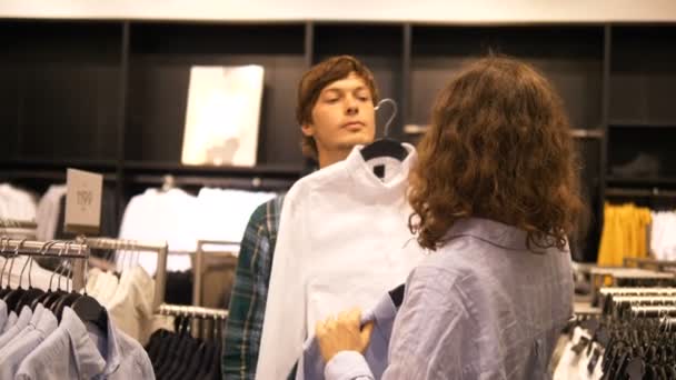 Una pareja casada en una tienda de ropa elige una camisa para hombre — Vídeos de Stock