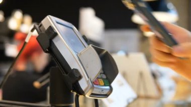 Bir kadın kasaya cep telefonuyla bir papazın yardımıyla ödeme yapıyor.