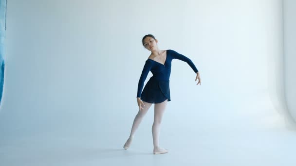 La atractiva bailarina realiza elementos de danza profesional sobre un fondo blanco — Vídeo de stock