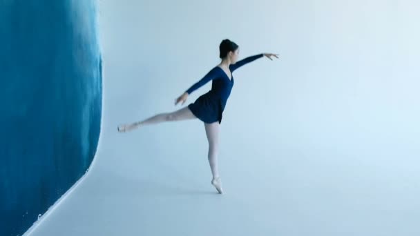 Молодая профессиональная балерина танцует на белом фоне в замедленной съемке — стоковое видео