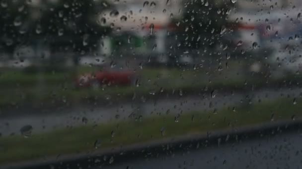 Vetro auto in gocce di pioggia durante la guida per le strade della città — Video Stock