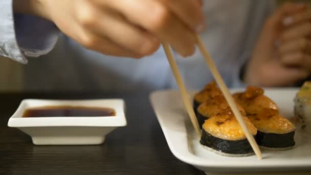 Frau legt gebackenes Sushi mit Lachskaviar in Sojasauce — Stockvideo