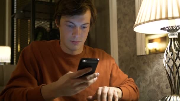 Man draagt bruine sweater surft internet met behulp van smartphone — Stockvideo