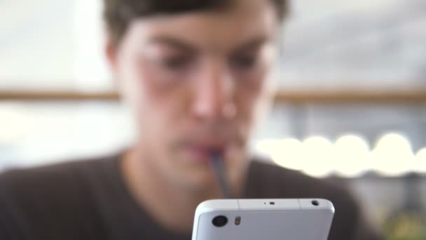 Knappe jongen drinkt vers sap en soorten op smartphone — Stockvideo