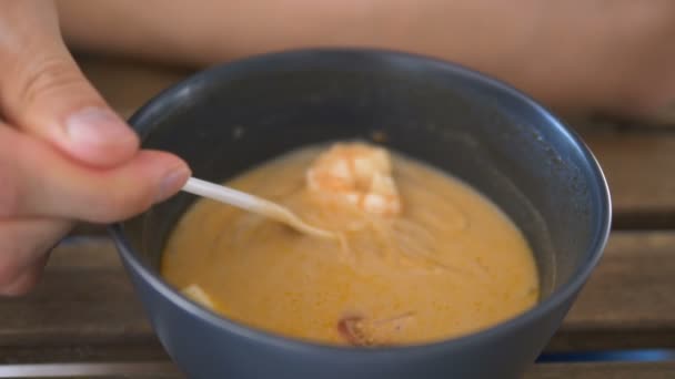 Person catches shrimp in soup with white spoon closeup — 비디오