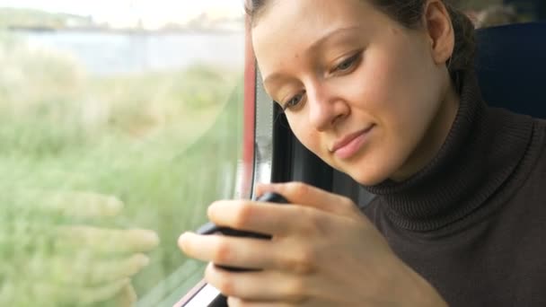 Mujer bastante joven mira a la pantalla del teléfono inteligente moderno — Vídeos de Stock