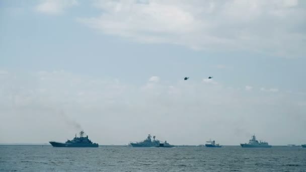 Helicopter silhouettes fly over naval vessels at parade — Stock Video