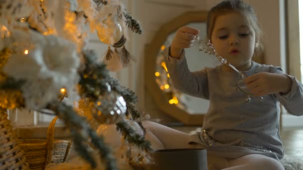 Intresserad småbarn flicka tittar på julgran dekorationer — Stockvideo