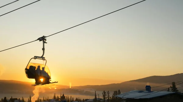 Silhouetten-Skifahrer erklimmen bei Sonnenaufgang den Sessellift — Stockfoto