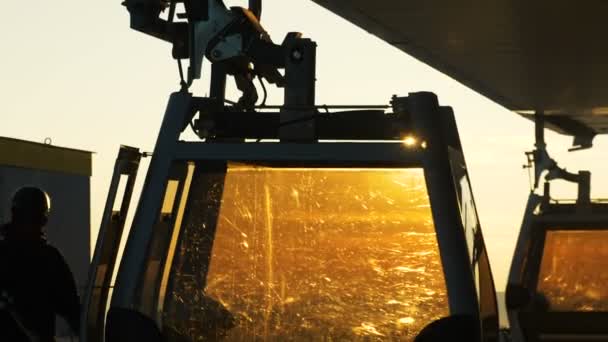 Esquiadores salen de las cabañas del telesilla de cerca contra una puesta de sol soleada — Vídeo de stock