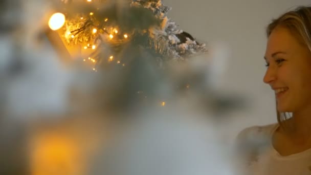 Anne ve küçük kız Noel ağacındaki çelenklere bakın. — Stok video