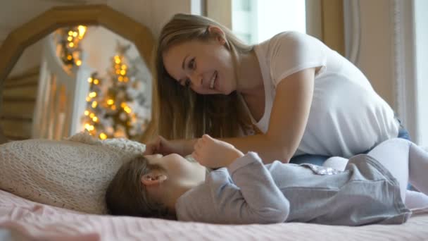 Hübsche junge Frau spielt mit kleinem Kind im Bett liegend — Stockvideo