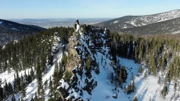 Picturesque rocky snowy hill peaks among forests aerial — Stock Video