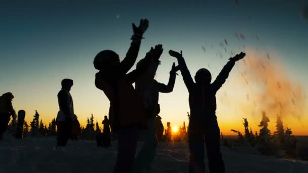 Örömteli emberek sziluettek dobja hó ellen fenyőfák — Stock videók