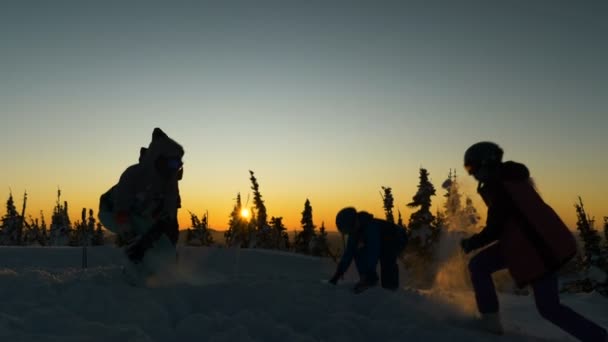 Joyful people silhouettes play snowballs on snowy meadow — Stock Video