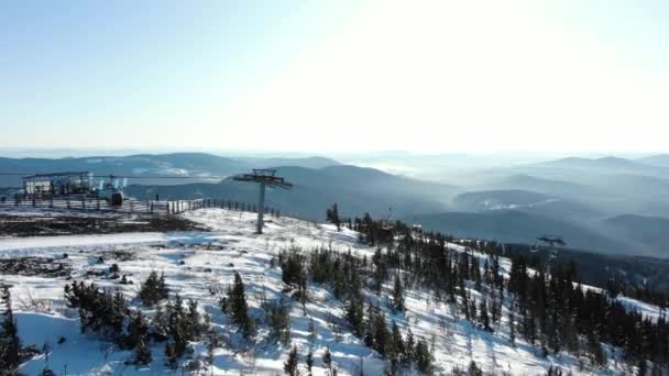 Bildrutestolsliftar över snöiga spår med vintergröna träd — Stockvideo