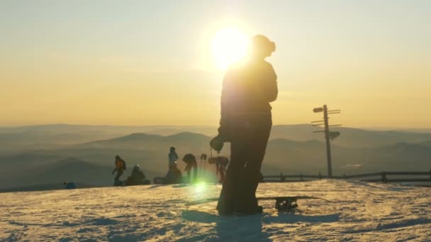 Turista activo con cielos snowboards siluetas al atardecer — Vídeos de Stock