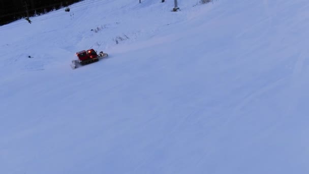 Modern red snowcat drives up white track under ski lift — 비디오