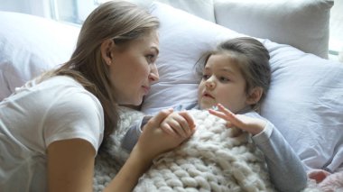 Harika anne ve kız yatakta yatarak iletişim kuruyor.